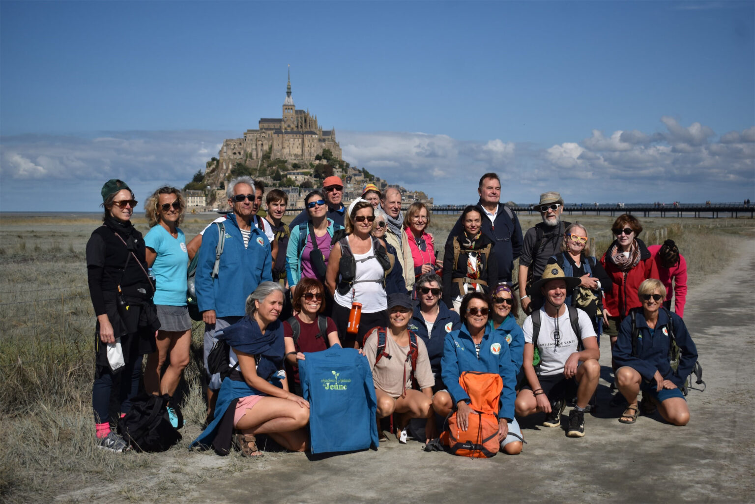 Groupe de personnes pratiquant le jeûne médical encadré devant le Mont-Saint-Michel, promouvant la santé et le bien-être.